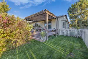 Back of property featuring a wooden deck, a fenced backyard, and a pergola
