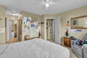 Bedroom featuring light carpet, a ceiling fan, and ensuite bath