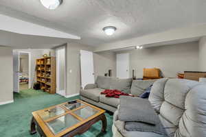 Carpeted living room with a textured ceiling and baseboards