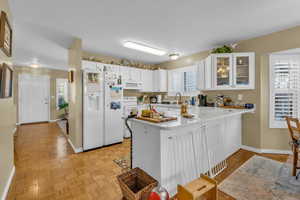 Kitchen featuring glass insert cabinets, white appliances, white cabinetry, a peninsula, and plenty of natural light