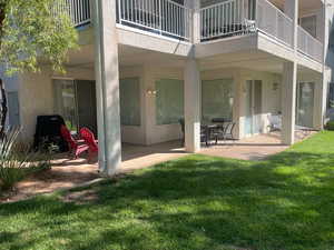 Rear view of property featuring a patio area, a balcony, stucco siding, and a yard
