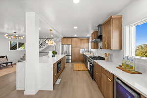 Kitchen featuring light stone counters, beverage cooler, light wood-type flooring, black appliances, and recessed lighting
