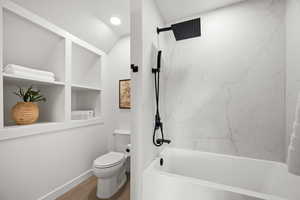Bathroom with a combined bath / shower with marble appearance, lofted ceiling, wood finished floors, and built in shelves