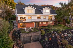 View of front of house with stairway, a balcony, concrete driveway, brick siding, and an attached garage