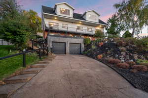 View of front of house featuring concrete driveway, an attached garage, and a balcony