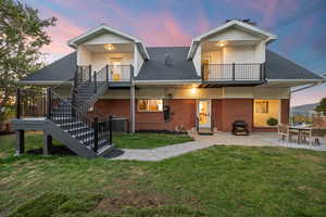 Back of property featuring a shingled roof, a patio, brick siding, and stairs