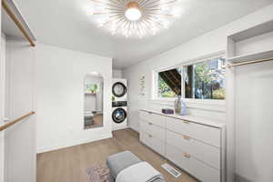 Walk in closet featuring light wood-type flooring and estacked washer and dryer