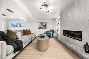 Living room with a fireplace, light wood finished floors, and a textured ceiling