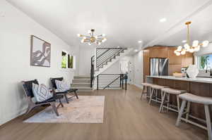 Living area with a chandelier, light wood-style flooring, stairway, and recessed lighting