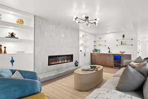Living area featuring built in features, light wood-style flooring, a tile fireplace, wet bar, and wine cooler
