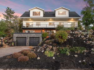 View of front facade featuring concrete driveway, a balcony, and a garage