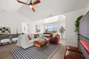 Living room featuring vaulted ceiling, light wood-style floors, ceiling fan, and a mountain view
