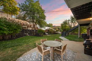 Patio terrace at dusk with a patio, outdoor dining area, and stairway