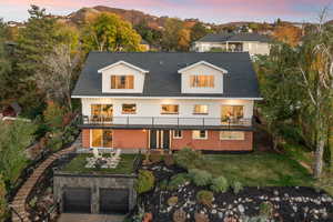 Back of house featuring a balcony, a yard, and a shingled roof
