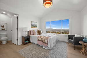 Bedroom featuring a mountain view, lofted ceiling, and light wood-style flooring