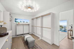 Spacious closet with light wood-style flooring and a chandelier