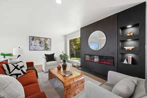 Living area featuring a glass covered fireplace, wood finished floors, built in features, and recessed lighting