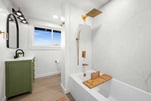 Bathroom with vanity, a combined bath / shower with marble appearance, and light wood-style floors
