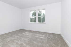 Carpeted spare room featuring baseboards