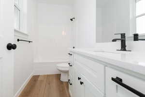 Full bathroom featuring vanity, light wood-style floors, and washtub / shower combination