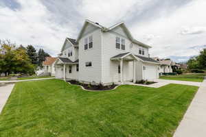 View of side of home with a yard, concrete driveway, a garage, and a residential view