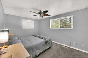 Bedroom with carpet floors, a ceiling fan, and a textured ceiling