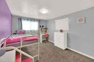 Carpeted bedroom featuring a textured ceiling and baseboards