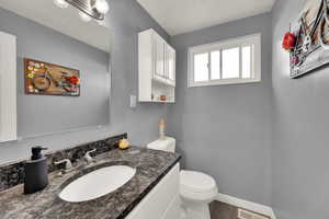 Half bathroom featuring a textured ceiling, vanity, and wood finished floors