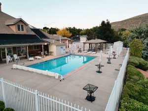 Community pool with a patio, a gazebo, and view of wooded area