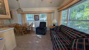 Living room featuring lofted ceiling, light carpet, and a chandelier