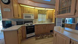 Kitchen featuring electric range oven, glass insert cabinets, white microwave, plenty of natural light, and ornamental molding