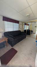 Carpeted living room featuring a drop ceiling