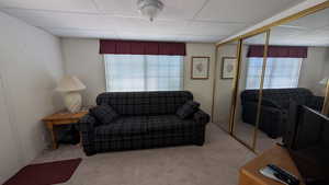 Carpeted living room featuring a drop ceiling