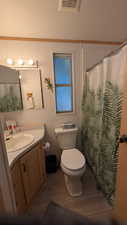 Full bathroom with a textured ceiling, curtained shower, vanity, light wood-type flooring, and crown molding