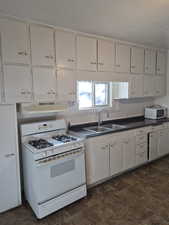 Kitchen with white appliances, dark countertops, and stone finish floors