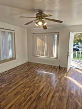Spare room with a textured ceiling, dark wood finished floors, and a ceiling fan
