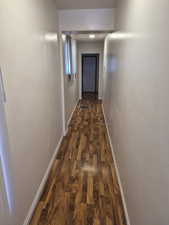 Corridor with baseboards and dark wood-style flooring