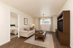 Living room featuring dark wood-style floors and a baseboard radiator. (virtually staged)