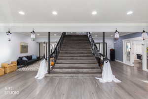 Staircase featuring wood finished floors, recessed lighting, and ornamental molding