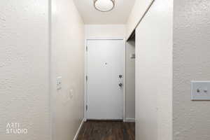 Doorway with a textured wall and wood finished floors