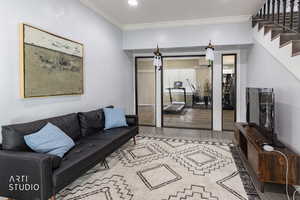 Living area with crown molding, wood finished floors, stairway, and recessed lighting