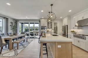 Kitchen with under cabinet range hood, recessed lighting, stainless steel appliances, tasteful backsplash, and a kitchen breakfast bar