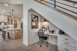 Office area featuring built in study area, light wood finished floors, and recessed lighting