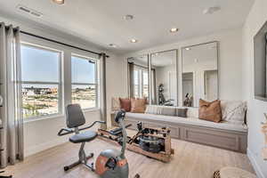 Workout room with recessed lighting, a water view, and light wood finished floors