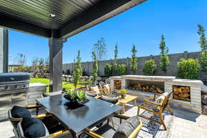 Fenced backyard with a patio area, outdoor dining area, and an outdoor stone fireplace
