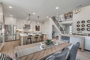 Dining space featuring stairway, light wood finished floors, recessed lighting, and a high ceiling