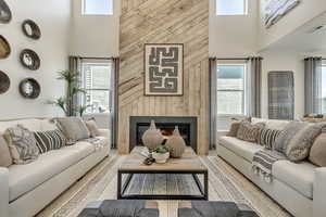 Living room with a towering ceiling, a fireplace, and wood walls