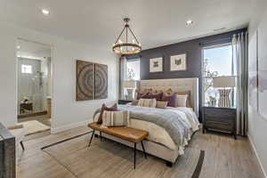 Bedroom featuring multiple windows, recessed lighting, light wood-style floors, a chandelier, and ensuite bath
