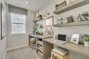 Office area featuring light wood-style flooring, built in desk, and recessed lighting