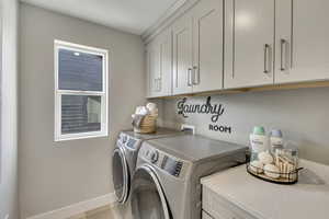 Laundry room featuring washer and clothes dryer, cabinet space, and tile patterned floors